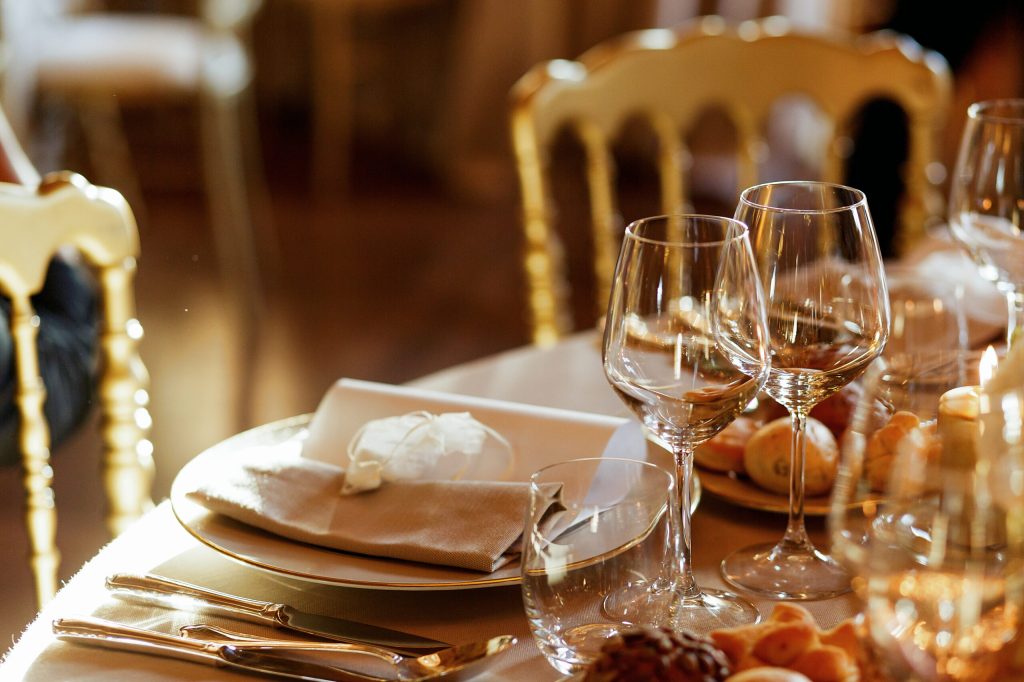 Close-up of shiny glassware standing behind dinner plate